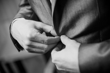 Businessman wears a jacket, groom getting ready in the morning before wedding. Black and white photography monochrome, correct button on jacket, hands close-up, man's style, stylish man