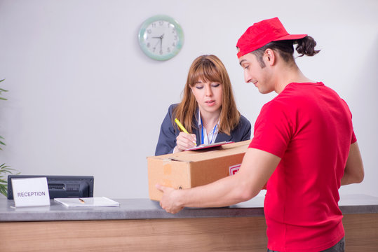 Young male courier delivering box to hotel's reception