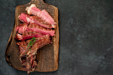 Grilled beef steak with spices on a cutting board on a stone background with copy space for your text