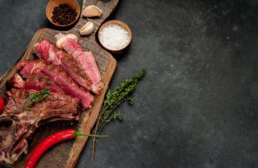 Grilled beef steak with spices on a cutting board on a stone background with copy space for your text