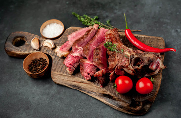 grilled beef steak with spices on a cutting board on a stone background