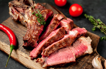 grilled beef steak with spices on a cutting board on a stone background