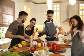 Happy people cooking food together in kitchen