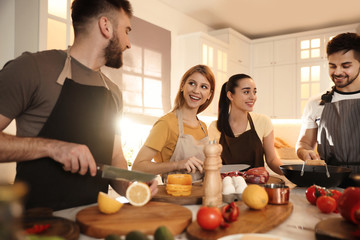 Happy people cooking food together in kitchen