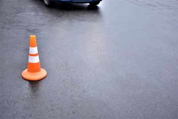 plastic cone for fencing on the road and an approaching car