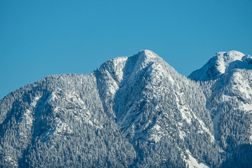 Obraz premium beautiful mountain range covered by the snow under the sun under clear blue sky