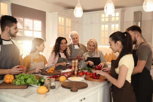 Happy people cooking food together in kitchen
