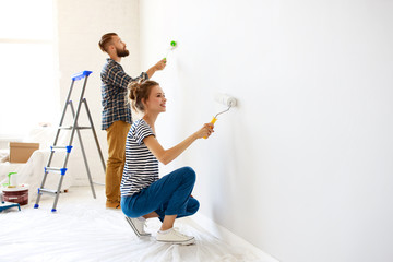 Happy couple painting wall together.