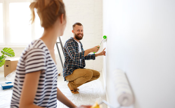 Happy couple painting wall together.