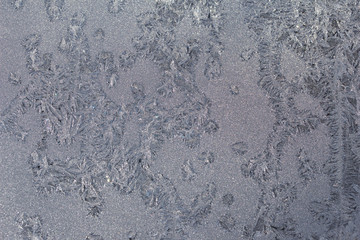 Crystal ice condensation patterns on a frosty glass window pane