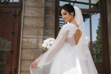 Gorgeous bride in elegant wedding dress with bouquet of white flowers in her wedding day