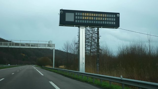 Coronavirus Sign on Information Screen on Highway. Windshield View while Driving Car. France March 2020. Slow motion