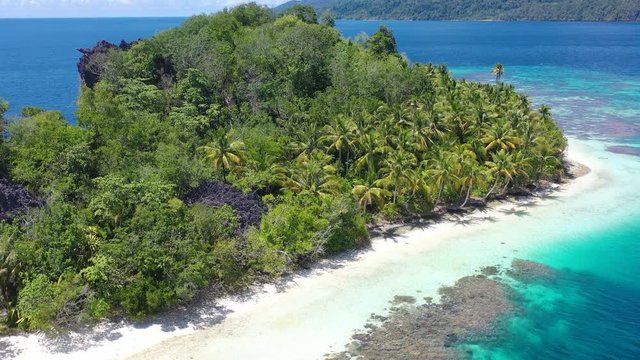 A remote, palm-covered island is found amid the gorgeous seascape in Raja Ampat, Indonesia. This amazing area is known for its marine biodiversity, world class scuba diving and snorkeling.