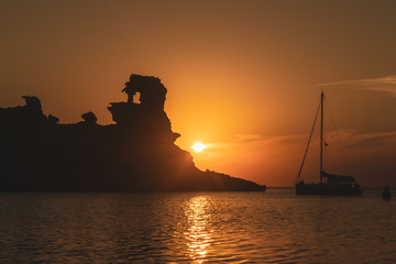 silhouttes of a rock and a boat infront the mediterranean sea in Menorca