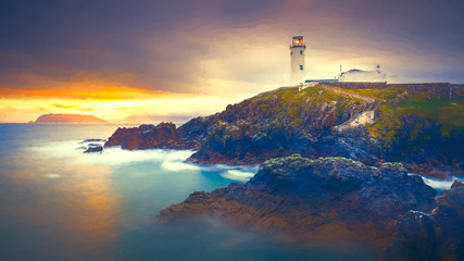Fototapeta premium Twilight yields to dawn, sunrise at Fanad Head Lighthouse with blurred water of Atlantic Ocean