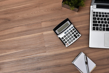wooden office desk with office utensils calculator laptop notepad top view with space for text