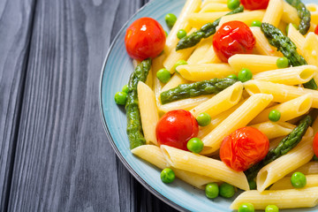 Penne pasta salad with asparagus , tomatoes and peas