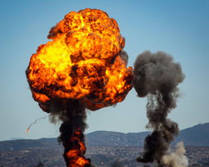 Ball and column of fire next to column of smoke from munitions explosion