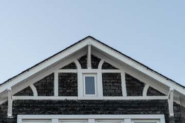 House facade covered in dark shake and shingle white, dividers, gable held by decorative brackets,...