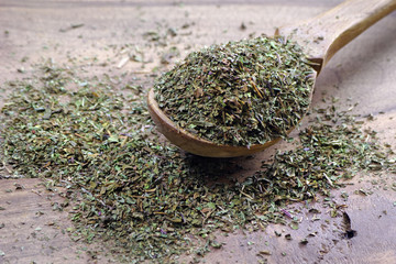 dried mint seasoning in a wooden spoon, close up