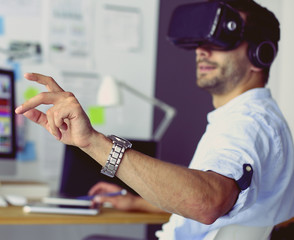 Young male software programmer testing a new app with 3d virtual reality glasses in office.