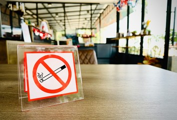 No smoking sign on a wooden table of coffee shop in hotel room. Concept photo of banning smoking in...