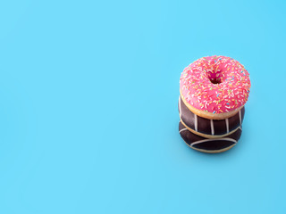 three sweet delicious fresh doughnuts stacked on top of each other in the form of a tower on a blue...