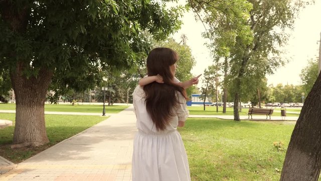 Beautiful mother carries a little daughter in park in open air. Beautiful mother and her baby are playing in park. baby and hugs happy mother. Happy Mother's Day Joy. Mom and baby. 4K