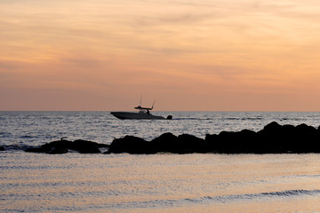 The silhouette of a small fishing boat floating on the Gulf of Mexico at sunset off the Florida coast.  