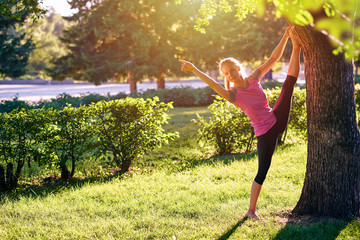 Yoga. Young woman practicing yoga or dancing or stretching in nature at park. Health lifestyle concept