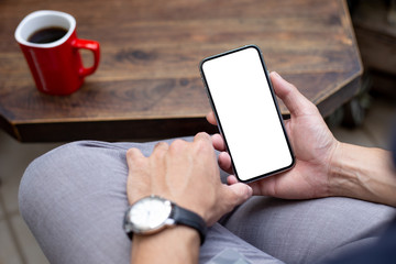 Mockup image blank white screen cell phone.man hand holding texting using mobile on desk at coffee shop.background empty space for advertise text.people contact marketing business,technology