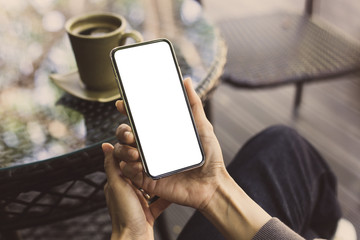 Mockup image blank white screen cell phone.woman hand holding texting using mobile on desk at coffee shop.background empty space for advertise text.people contact marketing business,technology