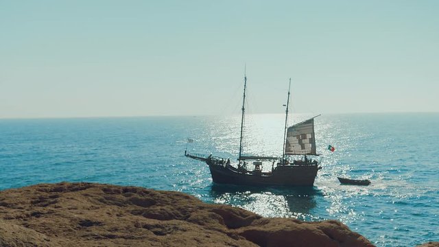 Slow-motion of pirate boat sailing near the beach on a sunny day. Large medieval ship on the sea.