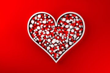 Heart shape filled with red pill capsules over red background - heart medicine, pharmacy industry or healthcare modern minimal concept