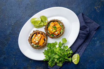 Sea Urchins caviar in shell with onion and cilantro. Top view. On trendy classic blue background