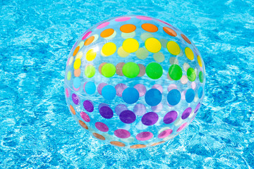 Inflatable colorful dotty Beach Ball Floating On Surface Of Swimming Pool blue water
