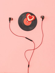 Red headphones, a vinyl disc and a heart on a pink background.