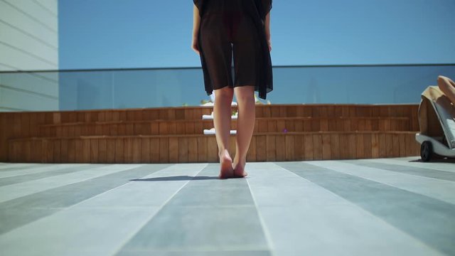young woman is walking towards the jacuzzi stairs on the terrace of the hotel room. she climbs the stairs and takes off her pareo in front of the jacuzzi. the king suit of the hotel.