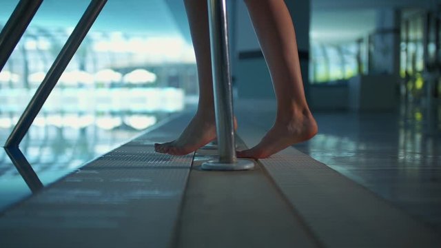 young girl is putting her foot in the indoor pool. Close-up of feet and legs. pushes the water with one foot. a relaxing image.