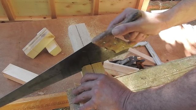 Man sawing a wooden block with a hand saw