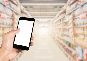 Hand using smartphone with blank screen on  Blurred shelf in supermarket.