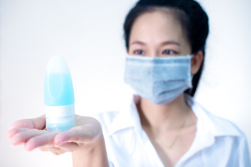woman wearing hygienic protective mask holding alcohol sanitizer gel standing on white background with copy space ,daily protection from corona virus or COVID-19 concept.