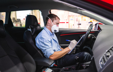 Technician doing a security inspection inside a vehicle protected with a mask and gloves to prevent...