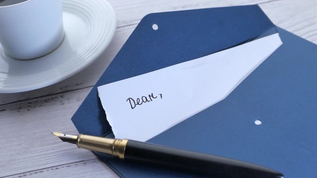 envelope and message on letter with pen and tea on table 