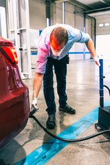 A technician doing an emission control of a security inspection of a vehicle protected with a mask and gloves to prevent the spread of virus
