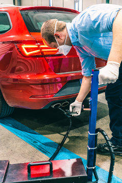 A technician doing an emission control of a security inspection of a vehicle protected with a mask and gloves to prevent the spread of virus
