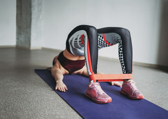 Attractive fit young woman sport wear fitness girl model doing stretching with elastic band make...