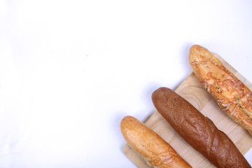 three baguettes on wooden cutting board on white background flat lay. Horizontal image