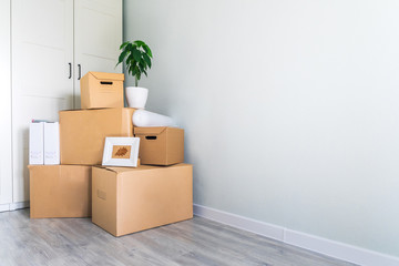Fototapeta premium A lot of cardboard boxes with things to move. Check-in to a new apartment or office. Wall and closet in a new empty apartment. Copy space