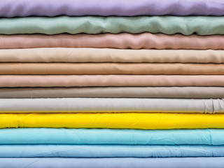 Layers of beautiful silk fabric in pastel colors in a store or factory, close-up. Samples of flowing silk for the buyer, designer, cutter for sewing an evening dress